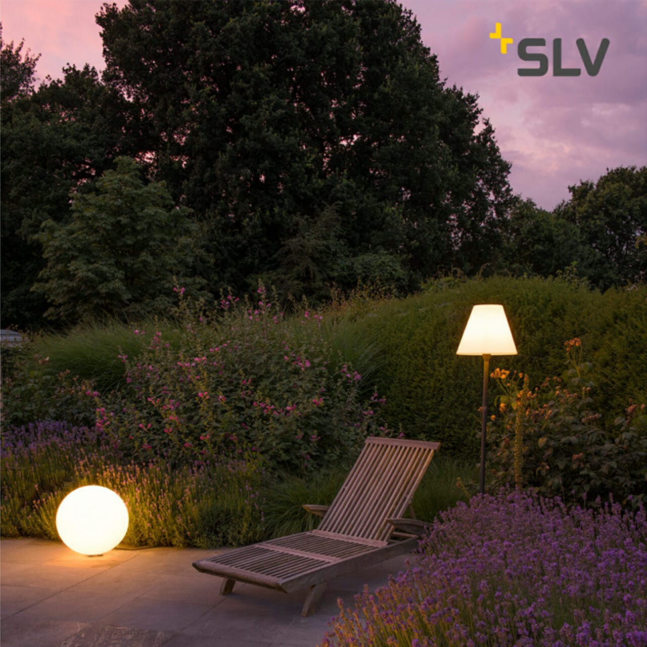 A wooden lounge chair stands on a patio surrounded by plants and flowers. A glowing sphere is on the ground next to a floor lamp, adding a modern touch. The SLV logo, reminiscent of a sleek digital company, is visible in the top right corner.