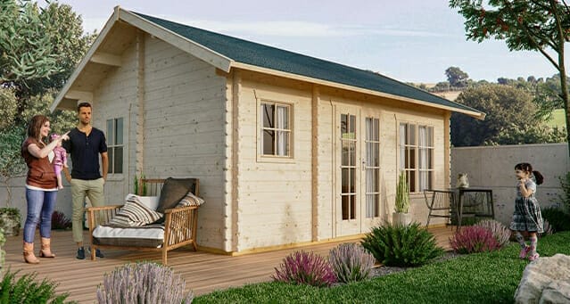 A wooden house with large windows and a front porch. A woman, man, child, and toddler are on the deck alongside outdoor furniture and lush garden plants from Kömpf Onlineshops.