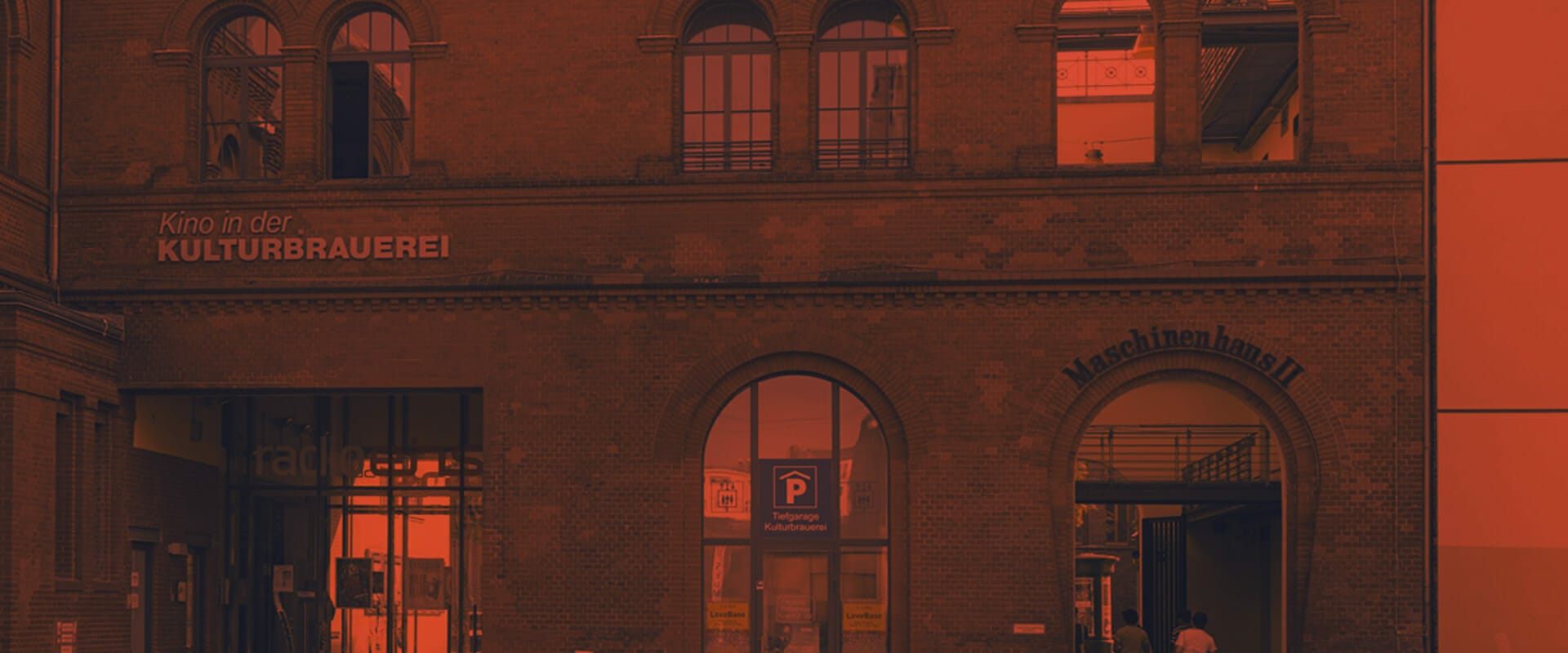 A brick building with signage "Kino in der Kulturbrauerei" and "Maschinenhaus II" above arched entrances. A parking symbol and a "rad" sign are visible near the lower left corner, adding a touch of local charm for visitors. Perfect for SEO enthusiasts seeking picturesque venues.