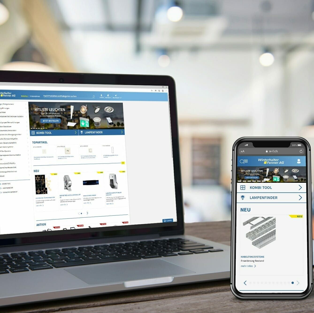 A laptop and smartphone display a website with product listings from Winterhalter+Fenner, featuring a search tool for lamps. The devices are placed on a wooden surface in a well-lit room.