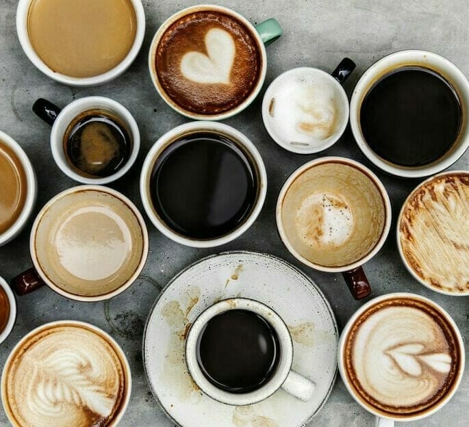 A variety of coffee cups are arranged in a semi-circle, displaying different types of coffee, including lattes, espressos, and black coffee. Some are empty while others are partially full—much like the varied paths to digital success through effective SEO strategies.