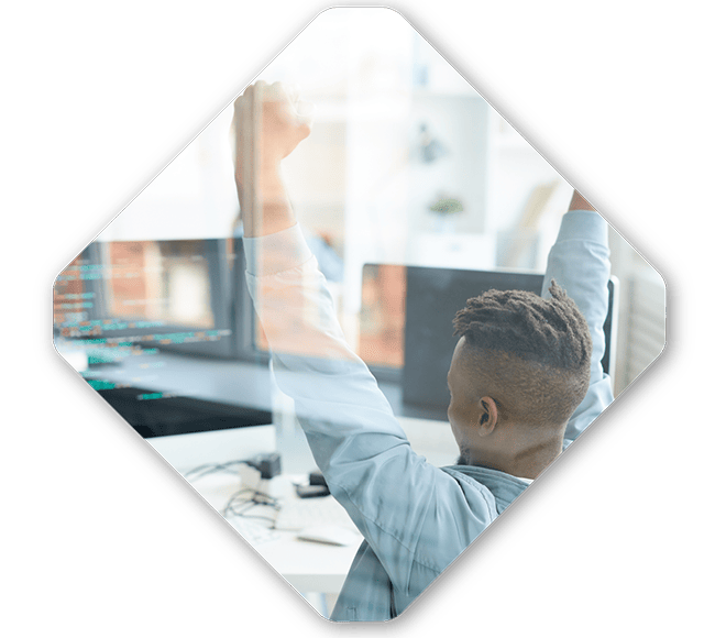 A person sitting at a desk in front of computer screens, perhaps debugging a complex state machine, raises their arms in a triumphant gesture in an office setting.