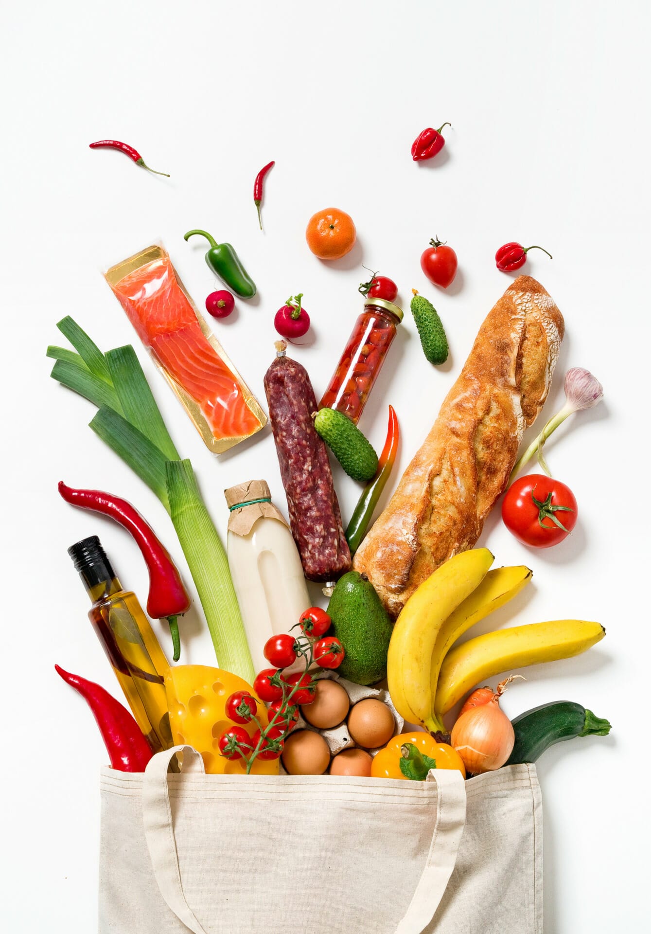 A cloth bag overflows with various groceries, including bread, fruits, vegetables, jars, eggs, and bottled items against a white background. Viabirds would find an array of delights in this bountiful scene.