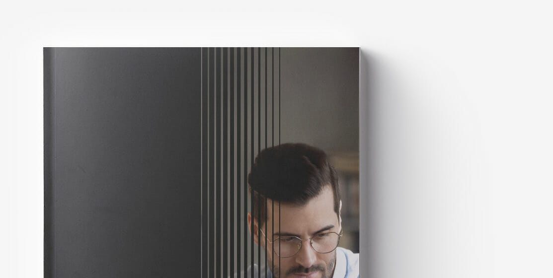 Person with glasses working behind a black striped glass partition, focusing intently on the delayed replatforming project.