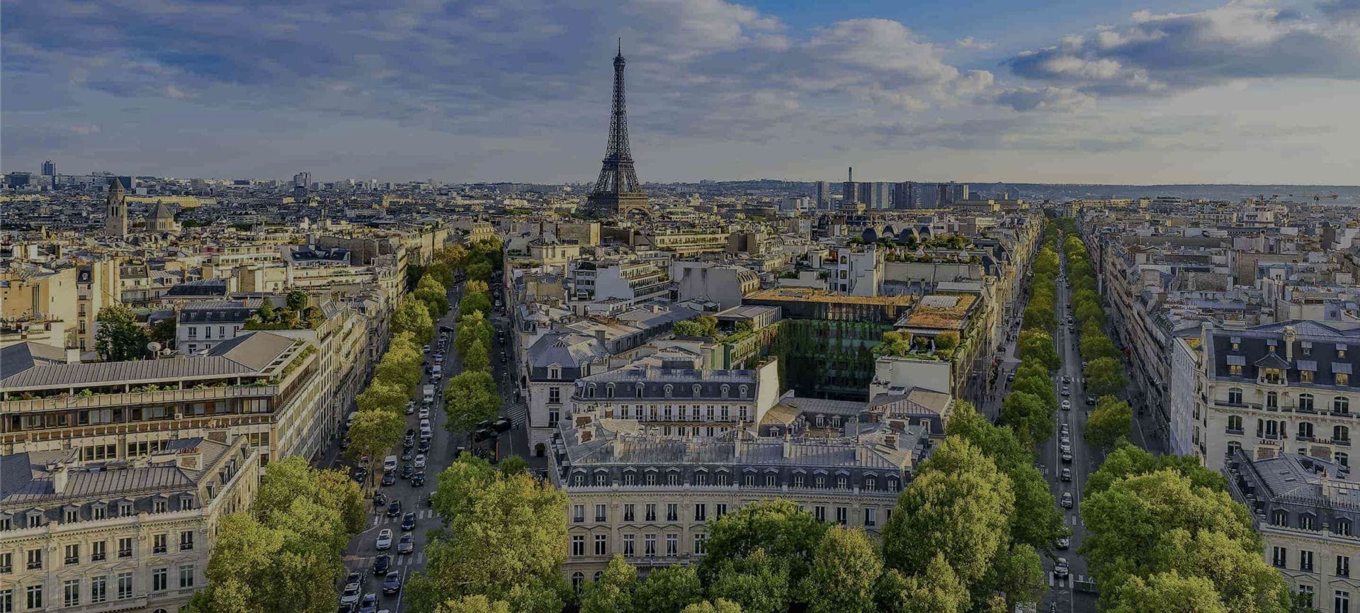 Aerial view of Paris showcasing the Eiffel Tower, surrounded by buildings, streets, and greenery under a partly cloudy sky. The city seamlessly blends its historic charm with modern tech for retail innovations.