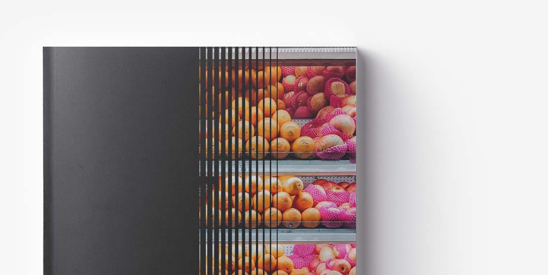 A book's spine partially overlaid with a photograph of shelves filled with oranges and pink wrapped fruits, creating a split visual effect, reminiscent of starting a grocery marketplace.