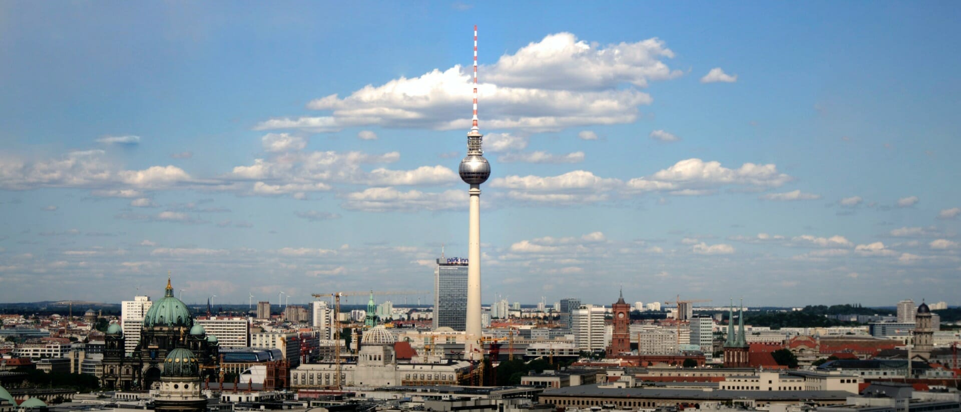 A view of Berlin's skyline featuring the Fernsehturm TV tower in the center, surrounded by various buildings under a partly cloudy sky, perfectly capturing the essence of Seamless Europe 2023.