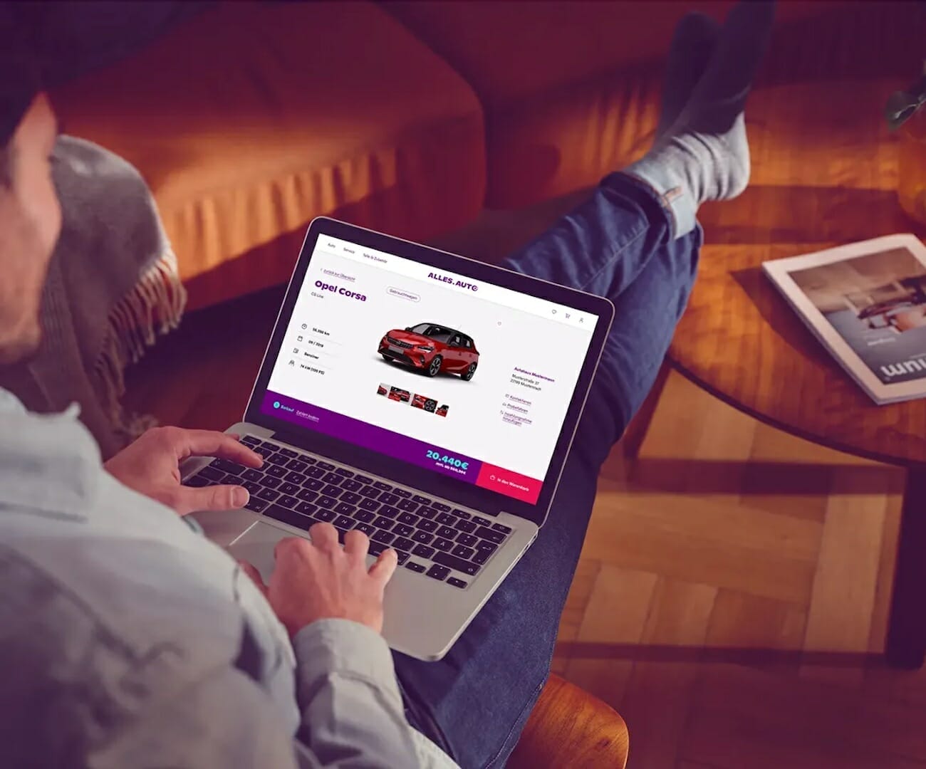 A person sits on a sofa with a laptop on their lap, browsing a car dealership website powered by spryker, displaying information about an Opel Corsa.