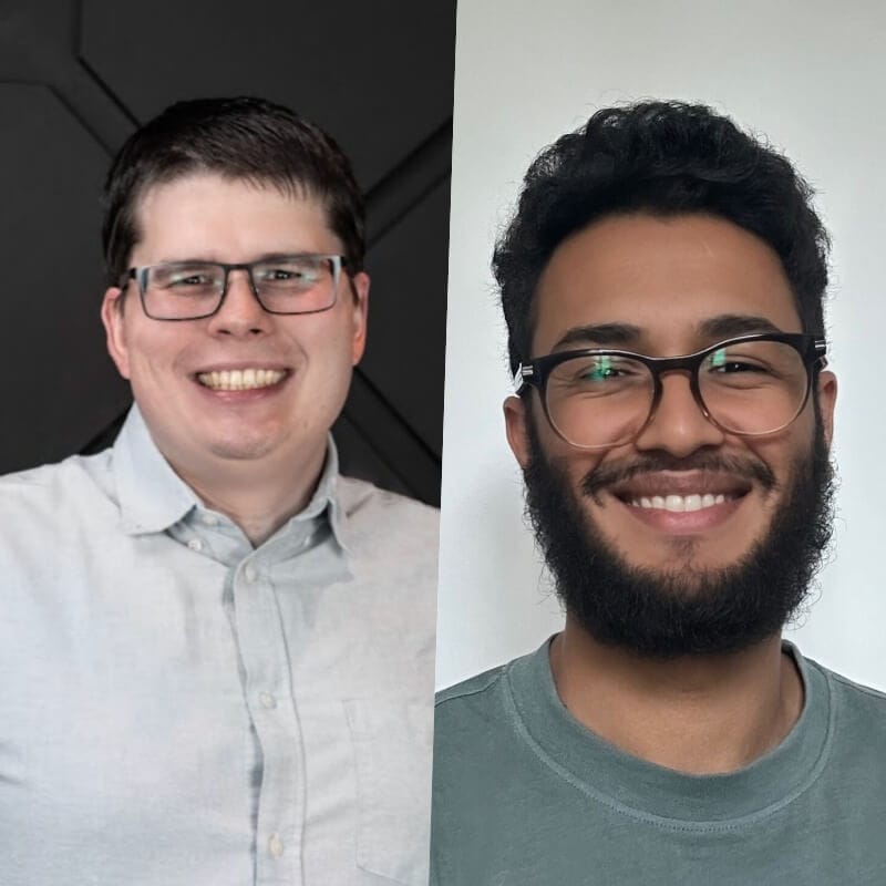 Two men with glasses and beards are smiling in a side-by-side portrait. The man on the left, dressed for Spryker EXCITE 2024, wears a light blue shirt and has short dark hair. The man on the right wears a green shirt and has curly hair.