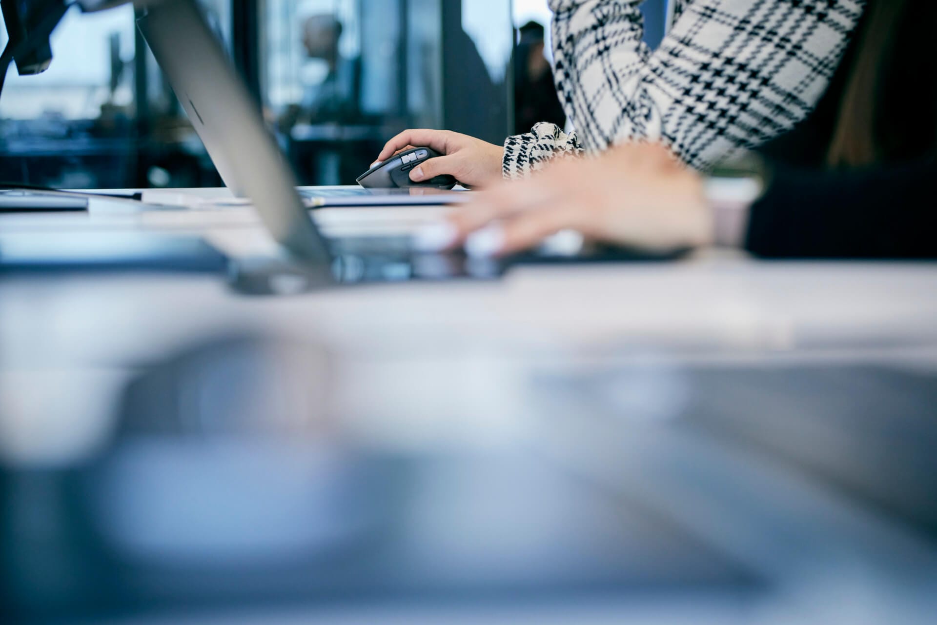 Two people working at a desk, using laptops and a computer mouse, collaborate on a Daimler Truck project with a blurred background and foreground.