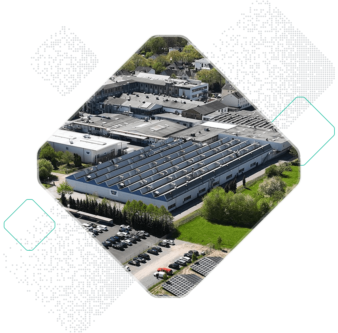 Aerial view of an industrial facility featuring Optibelt technology, surrounded by greenery, parking areas, and nearby residential buildings.